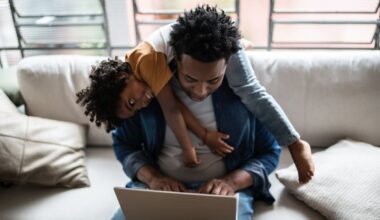 A person with a child sitting a computer.
