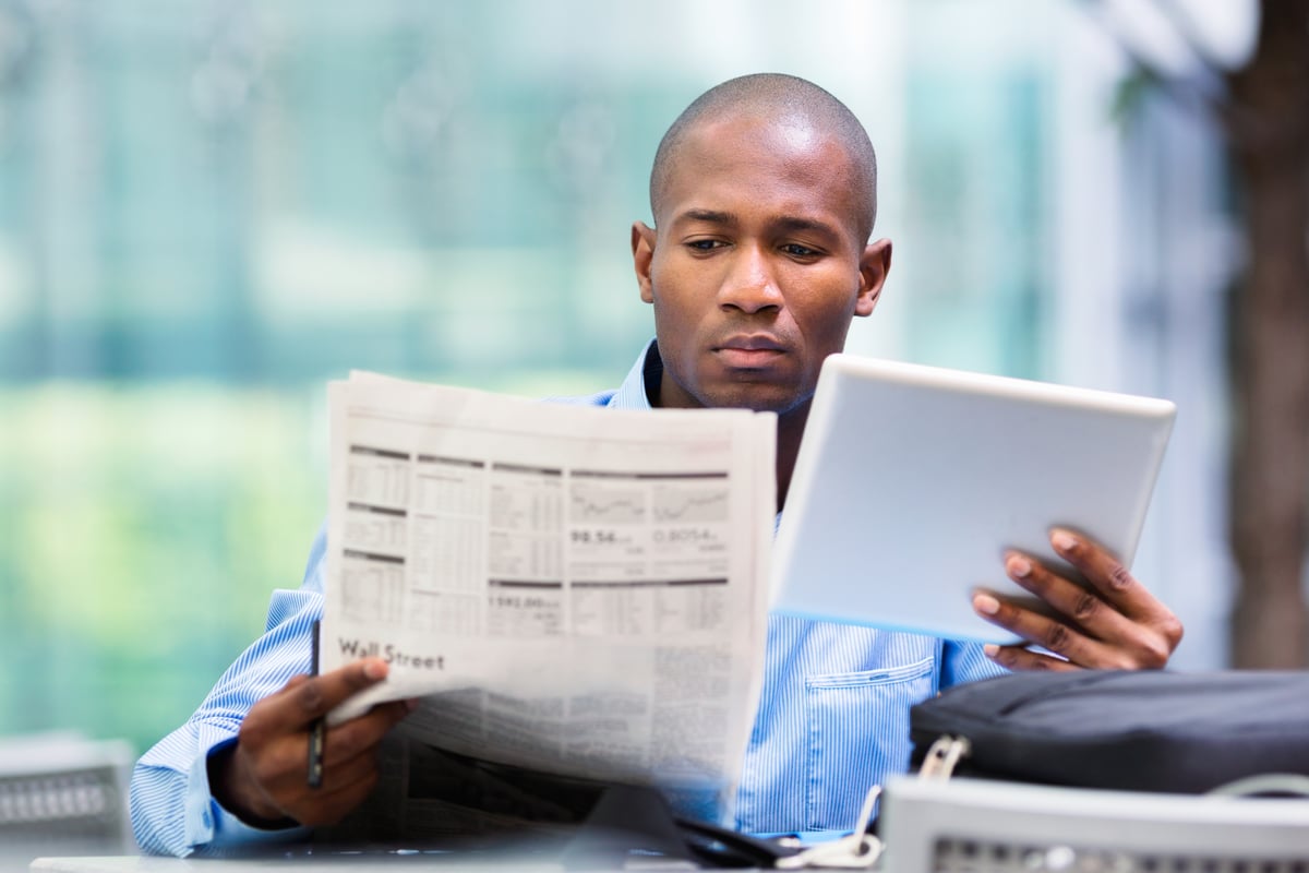 An investor is reading a financial newspaper.