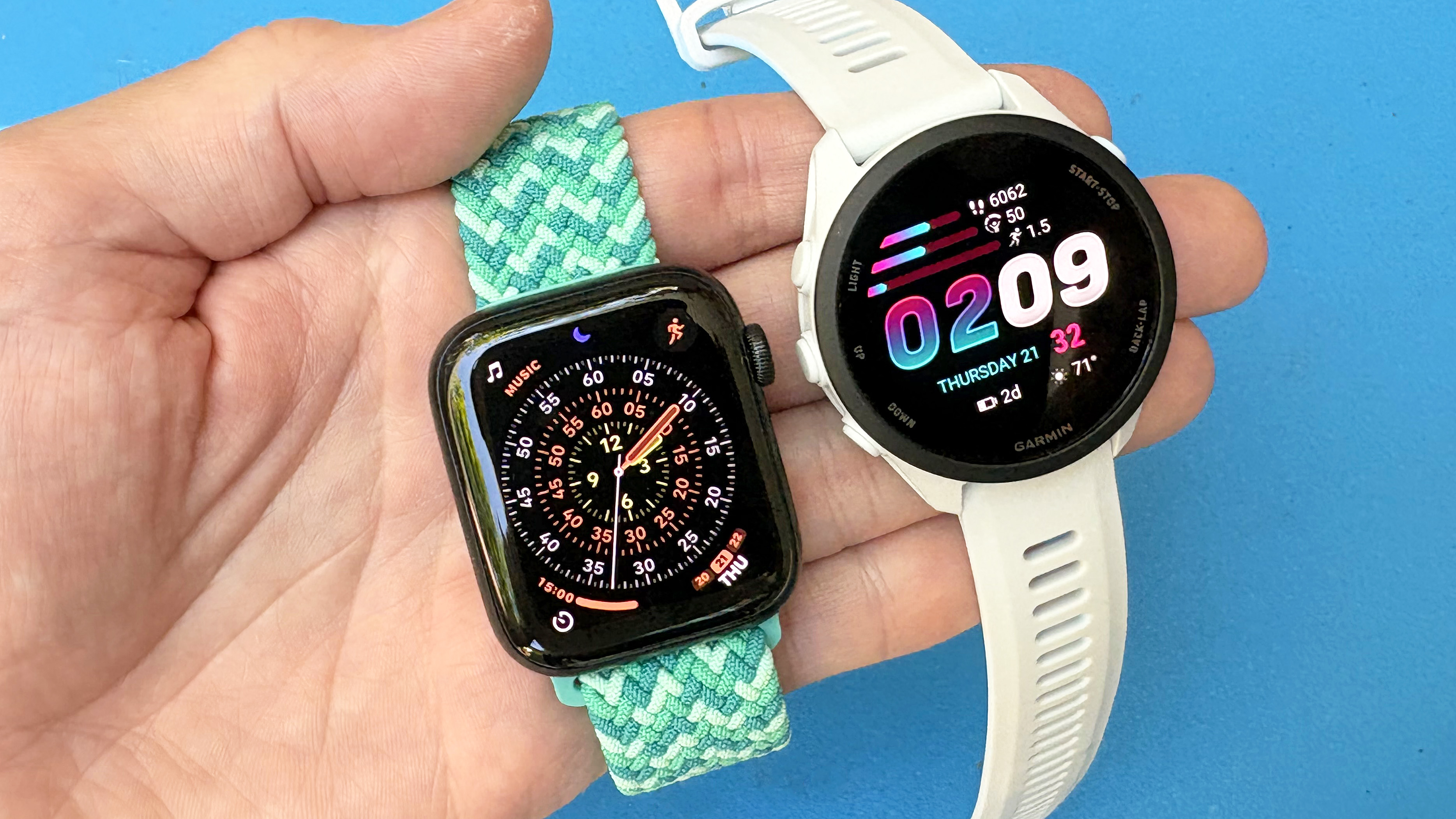 Close-up of the Apple Watch SE 3 next to the Garmin Forerunner 70