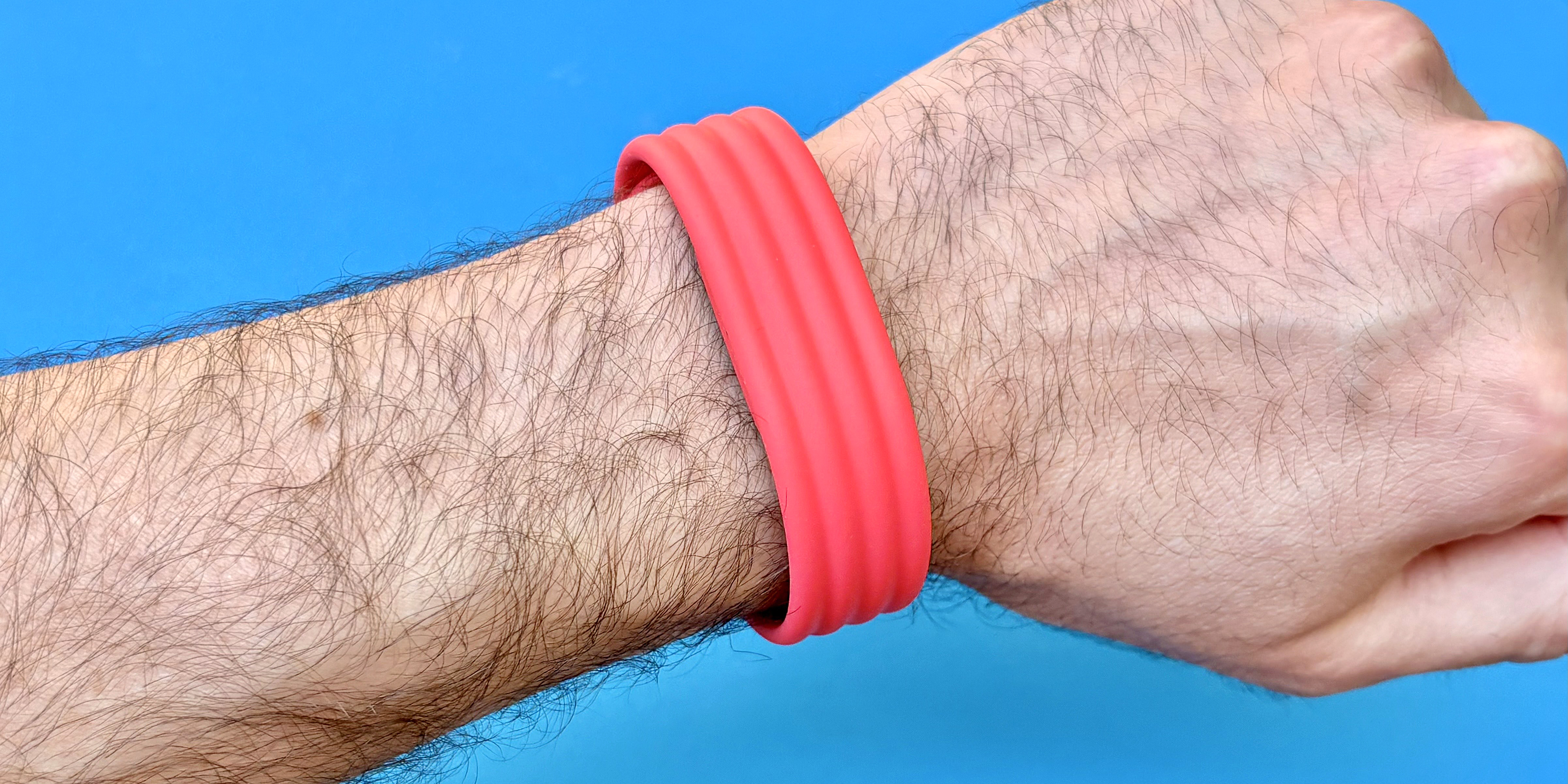 Close-up of the Fitbit Air on-wrist on a red strap against a blue background