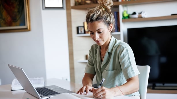 Beautiful young woman taking notes while learning from home