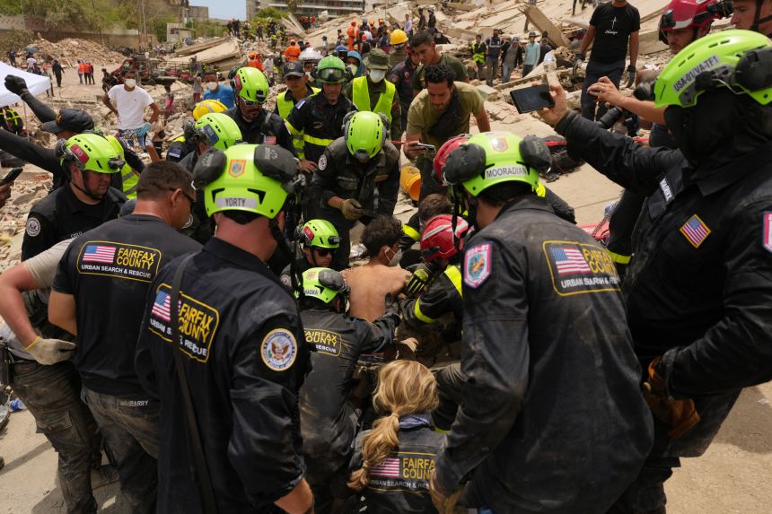 US firefighters from the Fairfax County, Virginia, search-and-rescue team pull a boy from the rubble after rescuing him and his father from a building that collapsed in the earthquakes in La Guaira, Venezuela, on Sunday, June 28, 2026.
