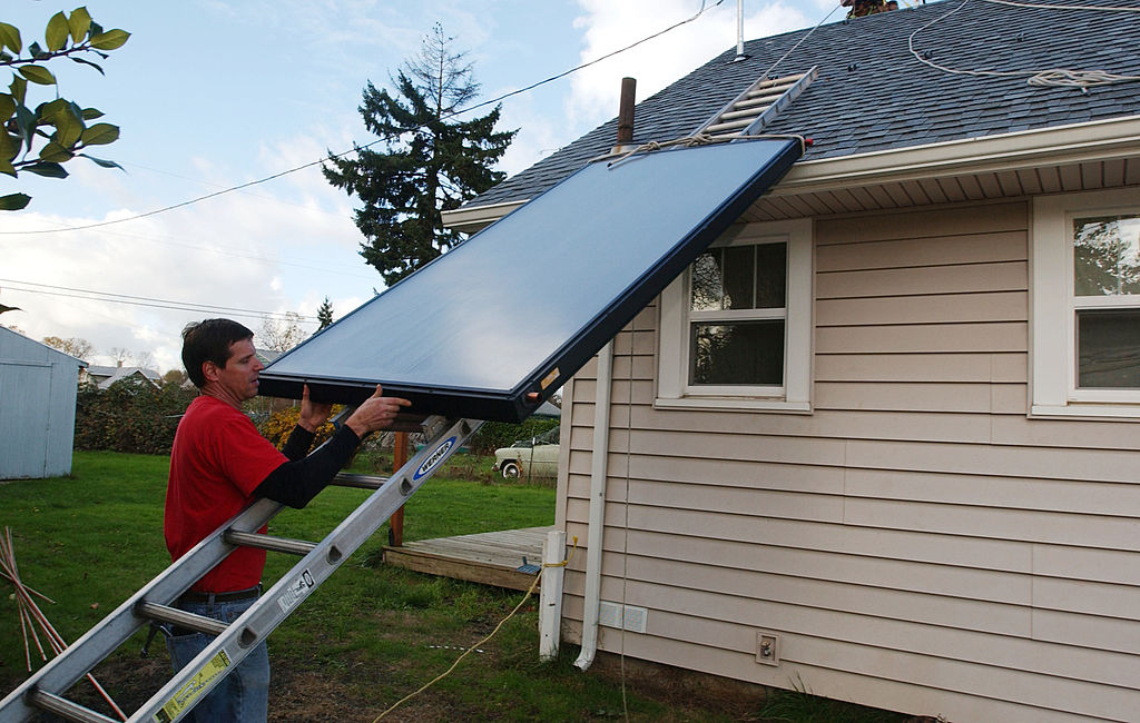 A man installs solar panels for a domestic hot water system in Salem, Oregon.