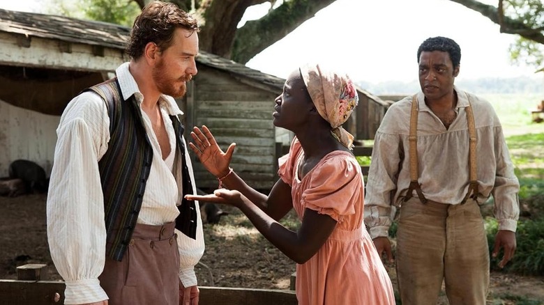 Patsey (Lupita Nyong'o) speaks closely to Edwin Epps (Michael Fassbender) as Solomon Northrup (Chiwetel Ejiofor) watches in 12 Years a Slave