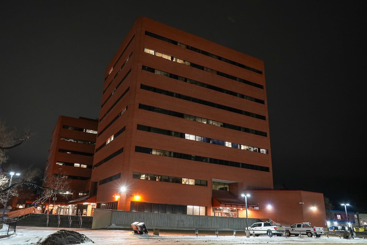Two tall orange brick buildings at night. Snow is on the ground.
