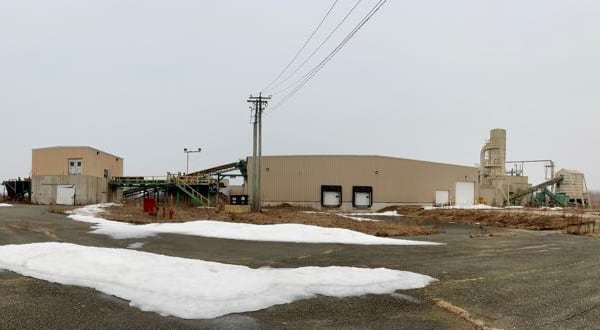 The outside aerial view of a large beige building that was formally a plywood manufacturing facility.