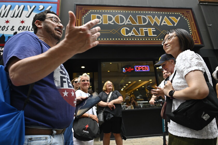 Tours guide Dan Goldrosen, left, talks to participants, including Xiao Stroming, outside the Broadway Cafe in the Loop, during a "Ferris Bueller’s Day Off" 40th anniversary walking tour.