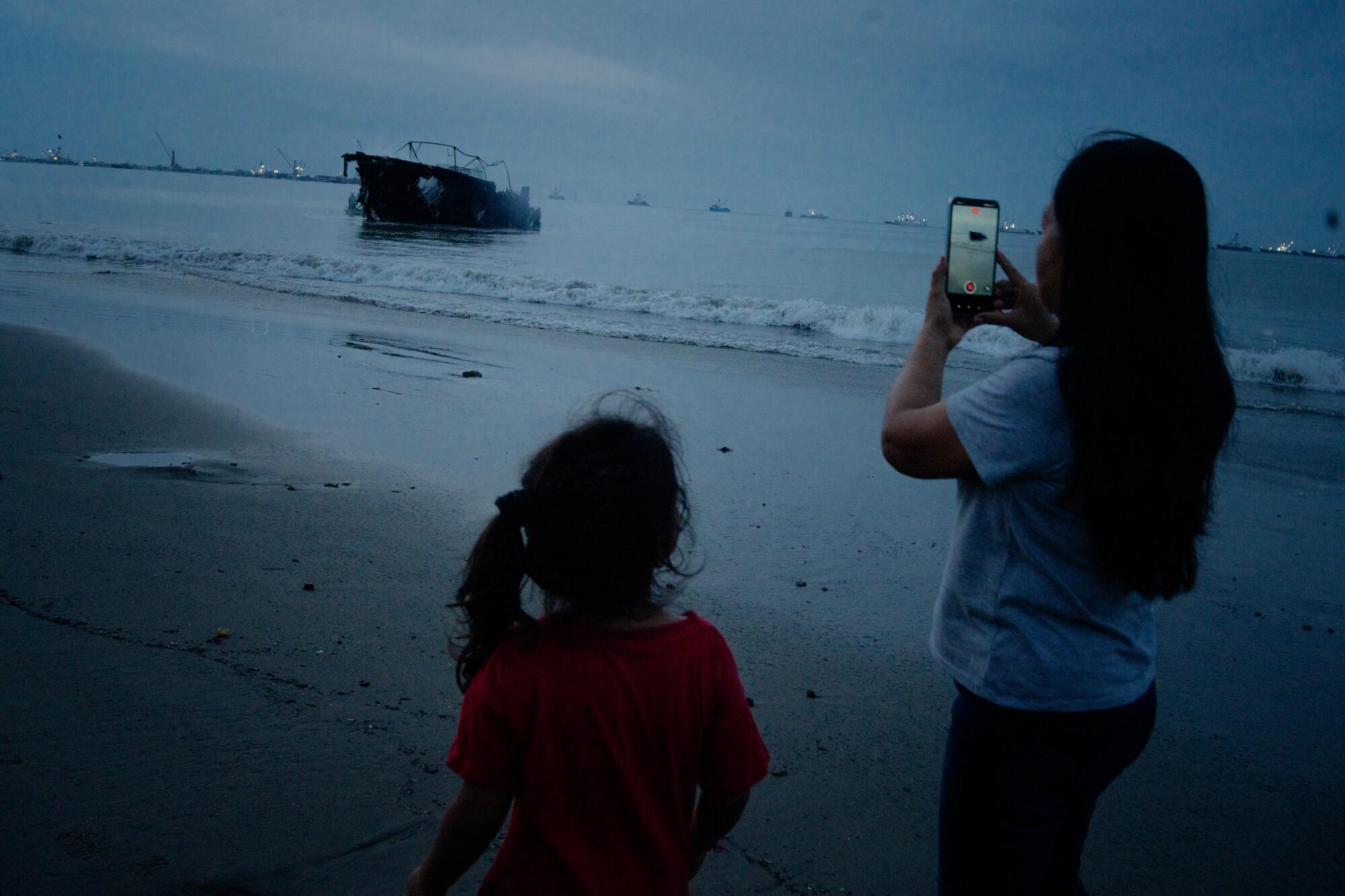 A mother and daughter from the local fishing community record a video of burning vessels