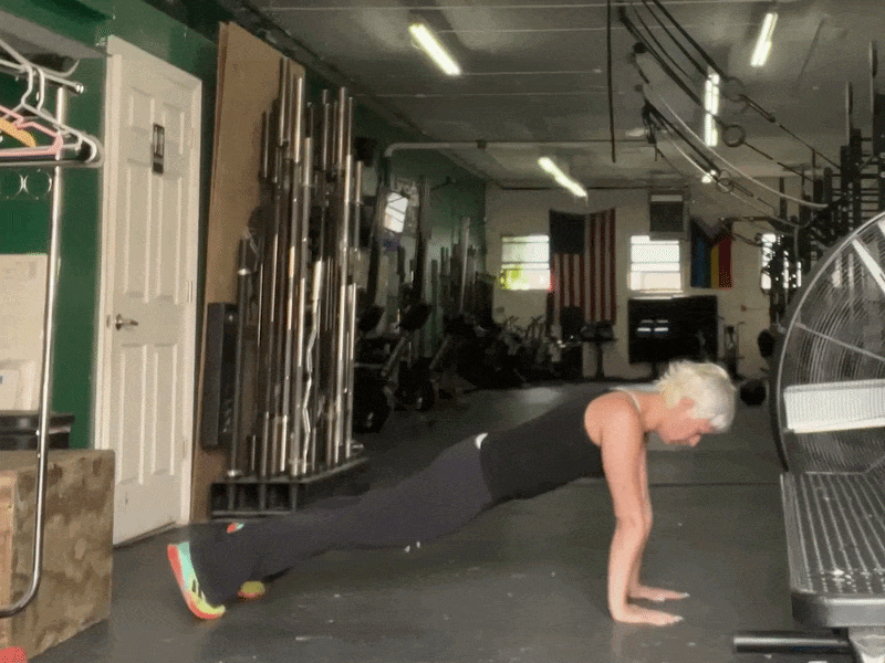 This is a photographic GIF showing a pushup exercise. In this exercise, position your body on the ground in the plank position. Bend your elbows to lower your chest, and then press back up.
