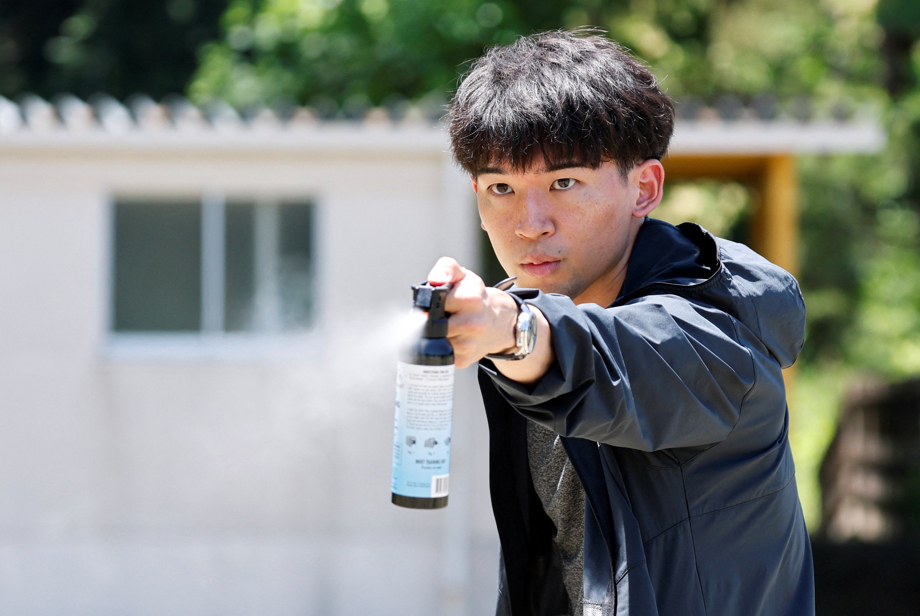 A participant uses a bear spray during an emergency response drill simulating a bear intrusion in Yaita