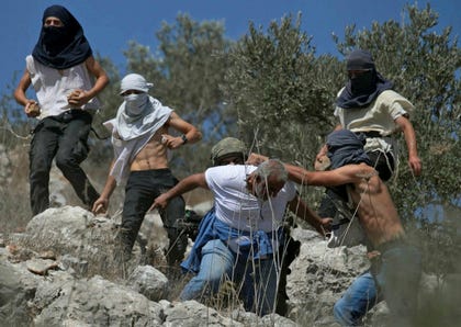 Masked Israeli settlers attack Palestinian olive farmers from the West Bank village of Hawara in this file photo from 2020. Credit: Jaafar Ashtiyeh/AFP Masked Israeli settlers attack Palestinian olive farmers from the West Bank village of Hawara in this file photo from 2020.