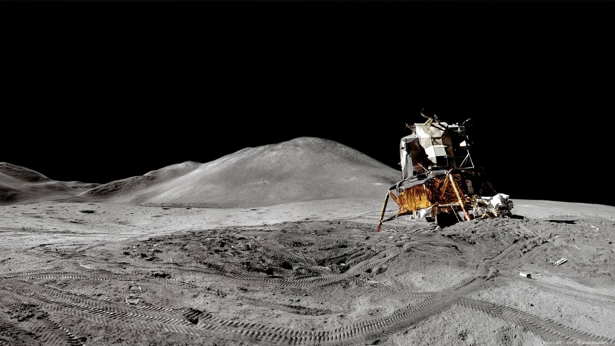 photo of a white and gold spacecraft tilting on the edge of a small crater on the moon