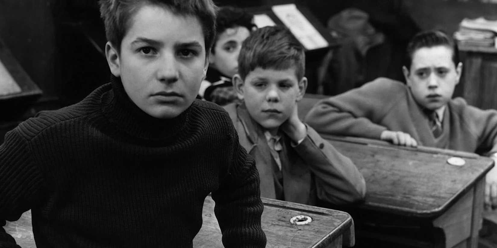 Young boys sitting at desks have sullen expressions in The 400 Blows.