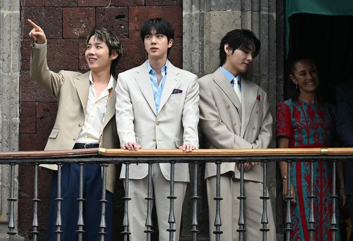 From left, J-Hope, Jin and V from K-pop boy band BTS acknowledge fans past Mexico President Claudia Sheinbaum from the balcony of the National Palace at Zocalo square in Mexico City, May 6. AFP-Yonhap