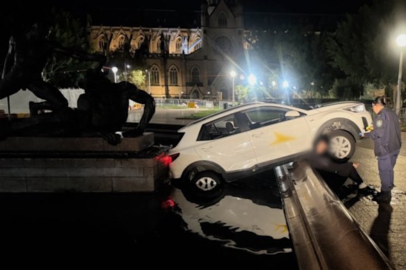 The driver sits against the edge of the fountain as police test for alcohol. 