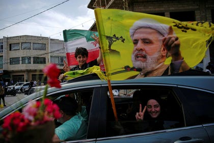Displaced residents of southern Lebanon waving a flag featuring Hezbollah leader Naim Qassem as they return to their villages after the April cease-fire. Credit: Hassan Ammar/AP Displaced residents of southern Lebanon waving a flag featuring Hezbollah leader Naim Qassem as they return to their villages after the April cease-fire.
