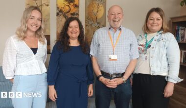 Four people stand in a room, three women and a man. They are Kayleigh Jones, Missing Link Service Manager for Oriana House, Sarah O’Leary, Missing Link CEO, Councillor Neil Hopkins, Swindon Borough Council, and Helen Brian, Albare Head of Mental Health. They are standing in a line smiling at the camera.