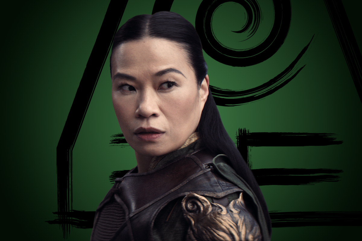 Lourdes Faberes as General Sung in detailed, armored clothing stands against a green background featuring a stylized symbol. She has long dark hair and an alert expression, suggesting a fantasy or action setting.