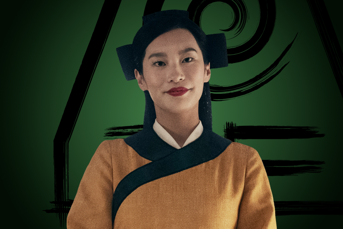 Amanda Zhou as Joo Dee in yellow and black outfit with traditional style, standing confidently against a green background with black geometric and swirl designs, suggesting a stylized, possibly fantasy or cultural setting.