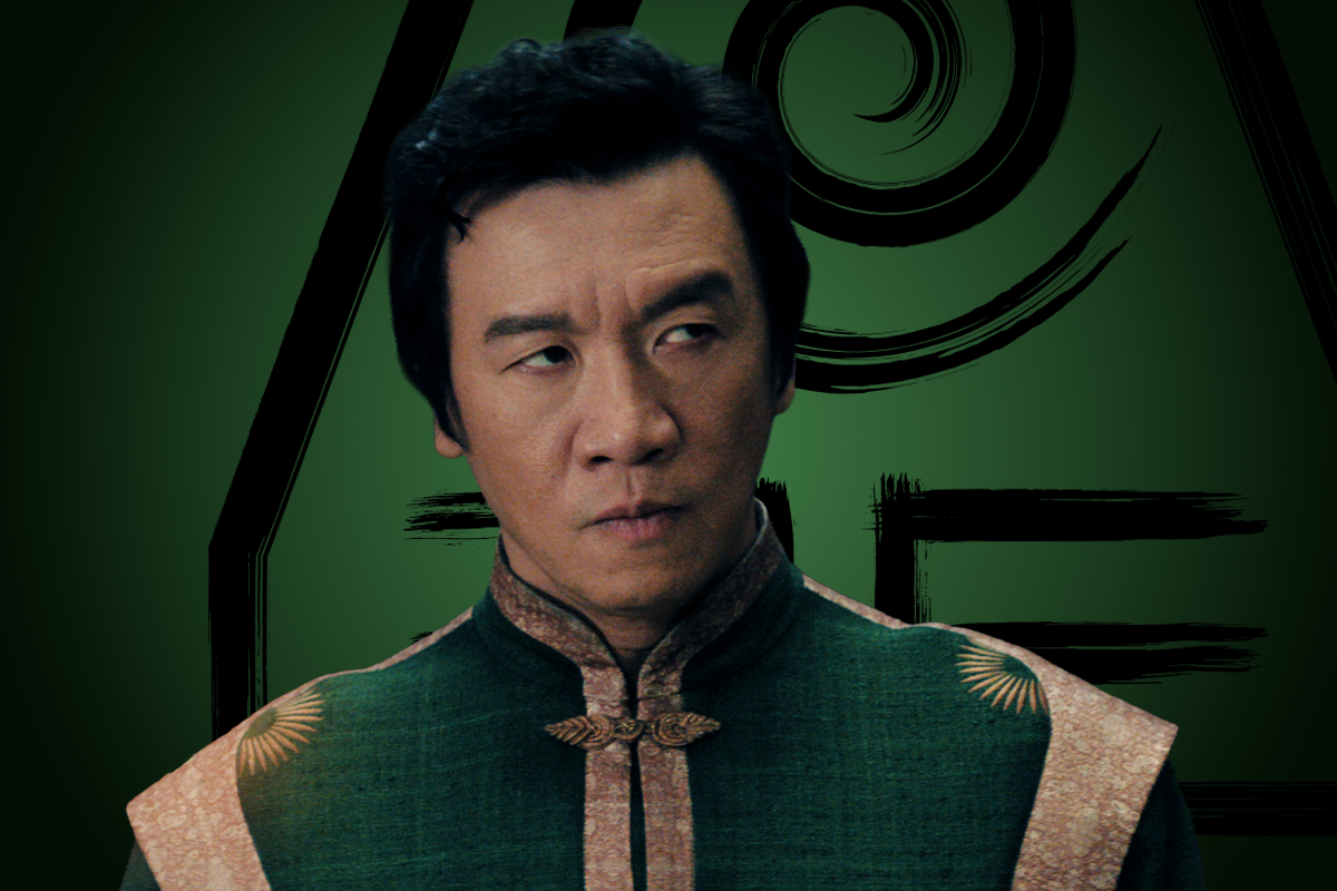 Chin Han as Long Feng in ornate green and gold clothing stands in front of a dark green backdrop featuring stylized, mystical symbols, giving a serious expression. The setting hints at a fantasy or historical environment.