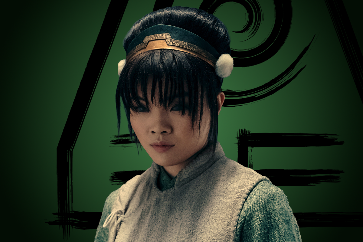 Miyako as Toph in traditional Earth Kingdom attire with a headband stands against a green background featuring an Earth Nation symbol, from a fantasy-inspired setting.