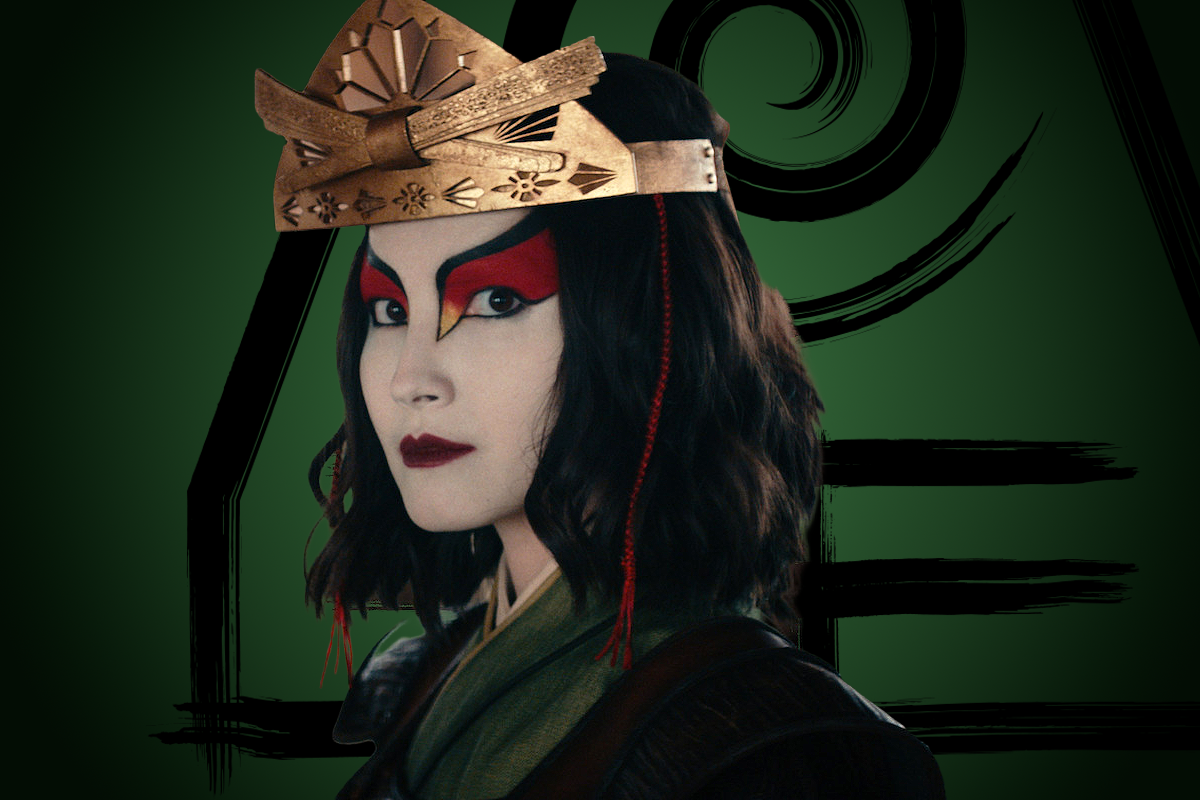 Maria Zhang as Suki in ornate red and black face paint and a golden crown stands against a dark green background with black artistic symbols, wearing traditional clothing and looking seriously at the viewer.