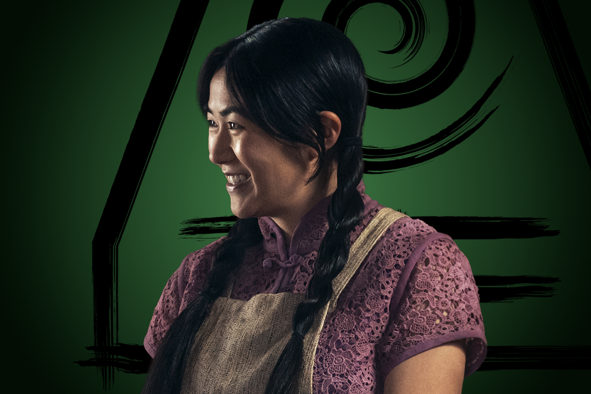Kelsey Lopes as Jin with braided hair, wearing a purple lace blouse and an apron, smiles while looking to the side. She stands in front of a green background with a bold, artistic swirl and geometric black shapes.