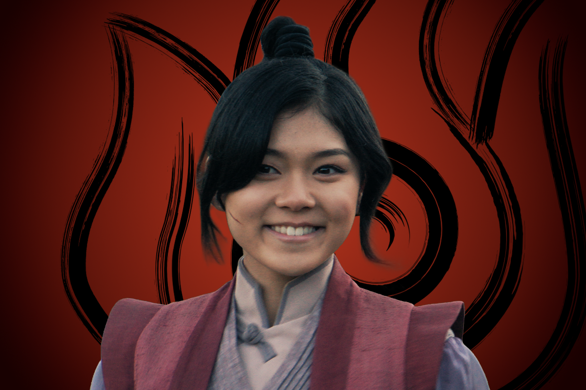 Thalia Tran as Mai smiling wearing traditional maroon and gray attire, stands in front of a red background with a large stylized black flame symbol, suggesting a fantasy or martial arts setting.