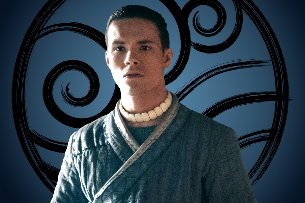 Ian Ousley as Sokka in a blue robe with a white bead necklace stands in front of a stylized black swirl pattern on a blue background, giving a fantasy or cultural vibe.