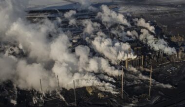 Seen from above, an oil and gas plant in Alberta billows smoke out of smoke stacks.