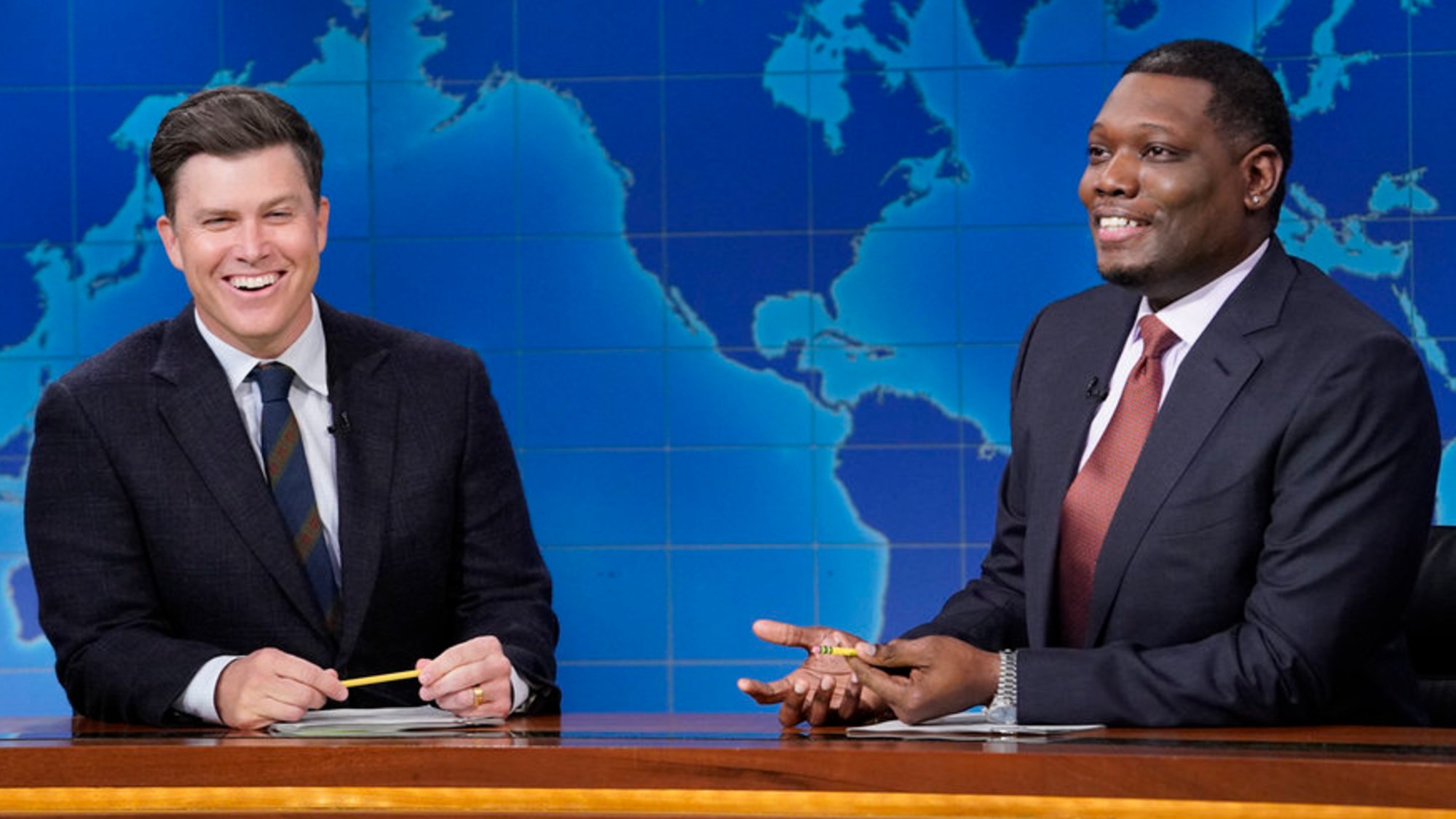 Colin Jost and Michael Che laughing on Weekend Update during the Season 51 finale of SNL.