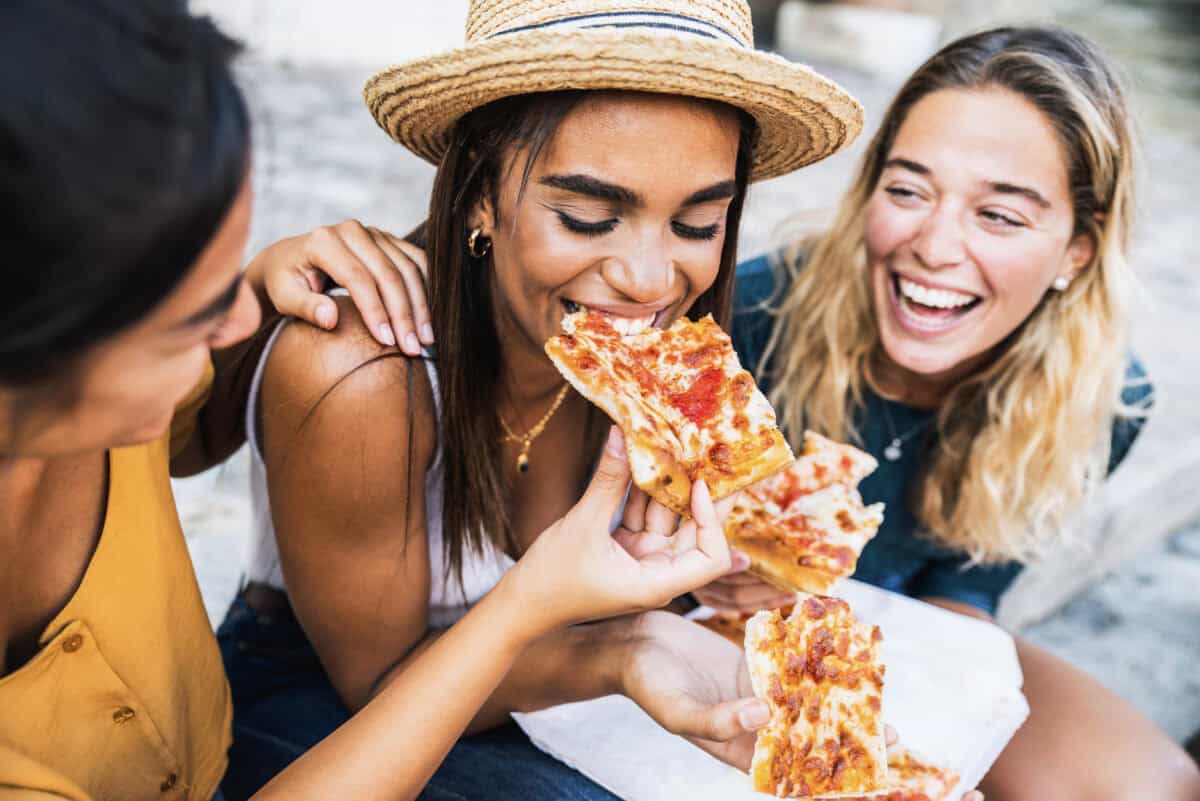 three friends eat pizza