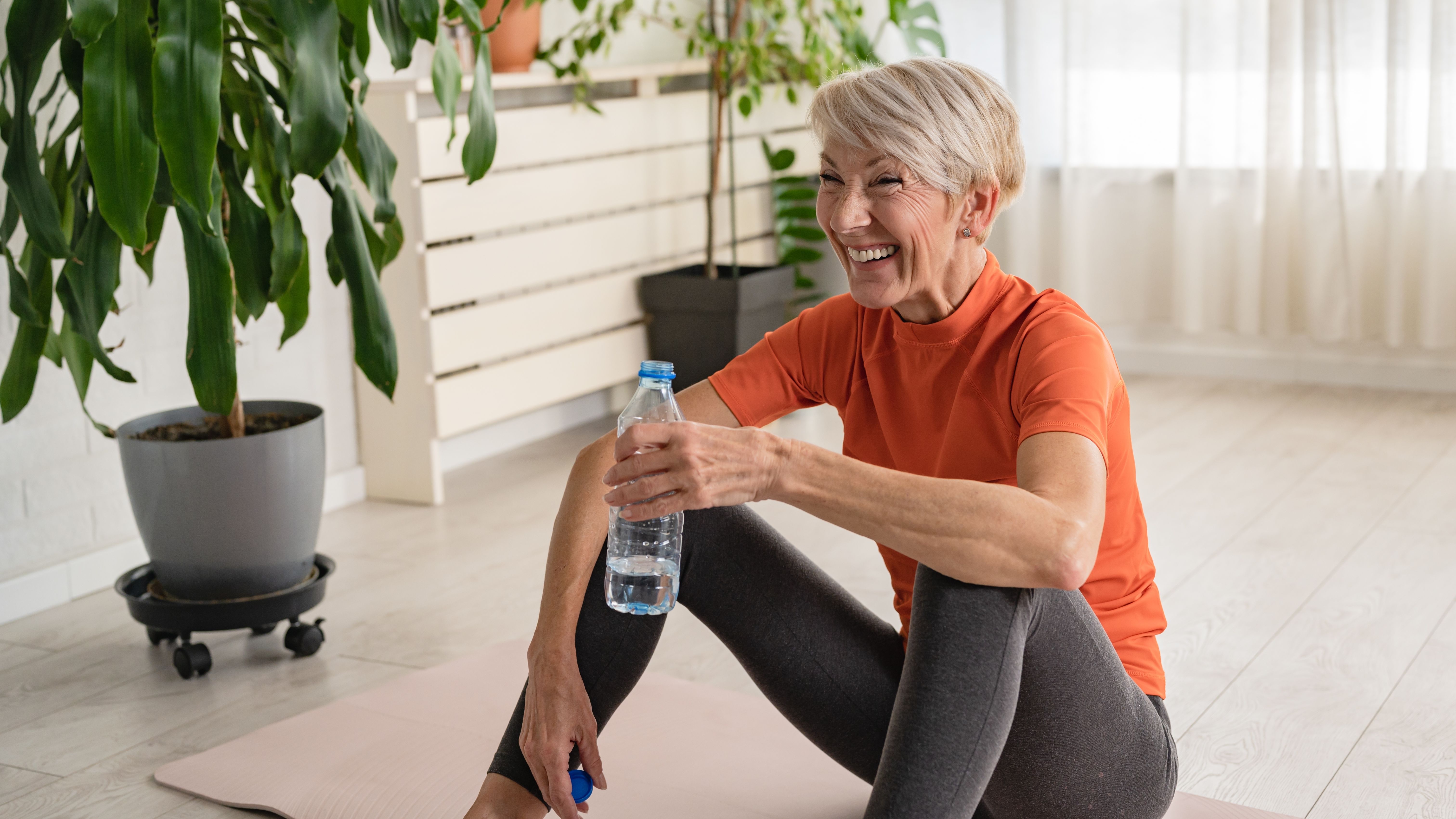a senior woman smiling on a workout mat