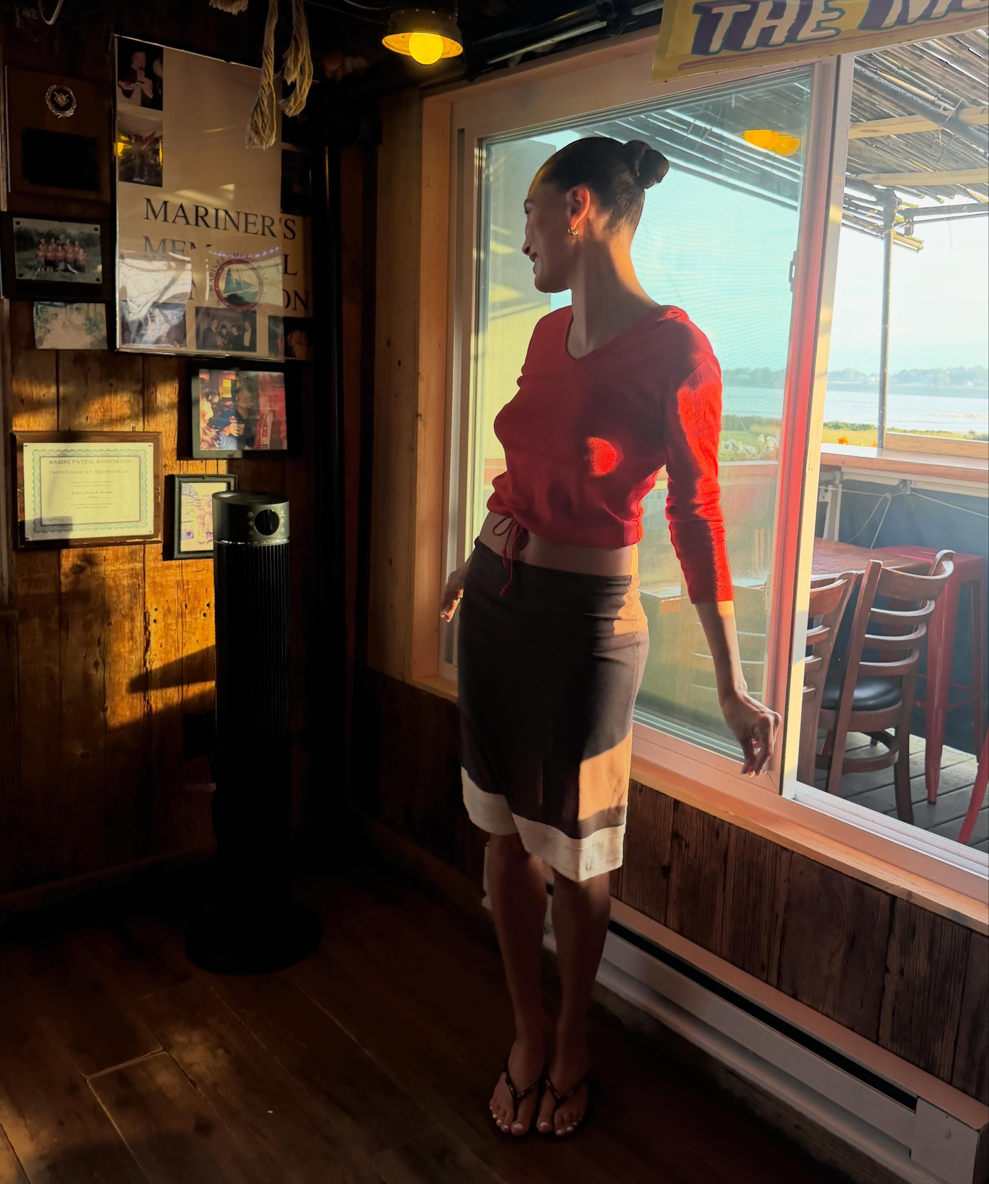 Hailey Bieber at her Rhode Island event wearing a red top and brown skirt with Staud thong sandals.