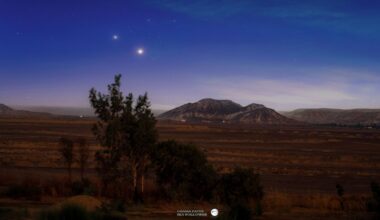 Two bright star-like planets are photographed shining side by side above mountains in a tranquil plain.