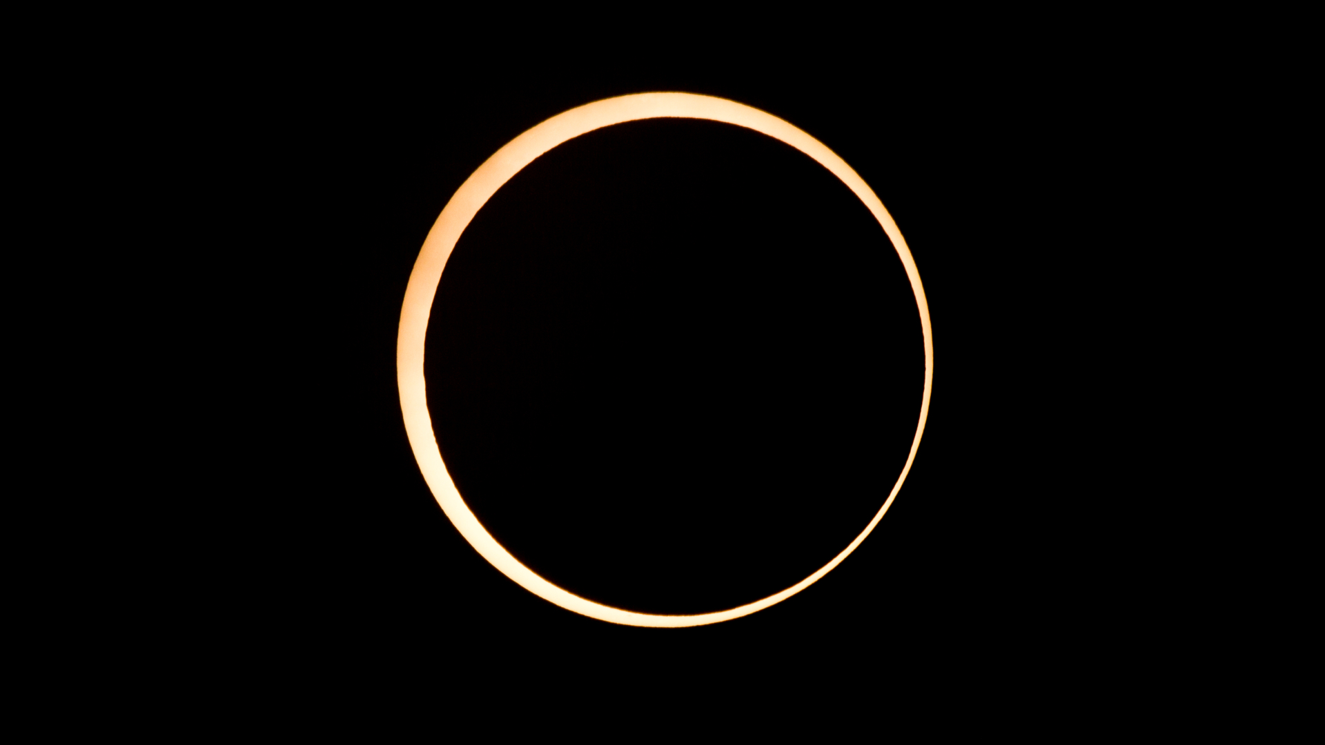 A photo of the moon's silhouette surrounded by the outer edge of the sun in a black sky during a total solar eclipse.