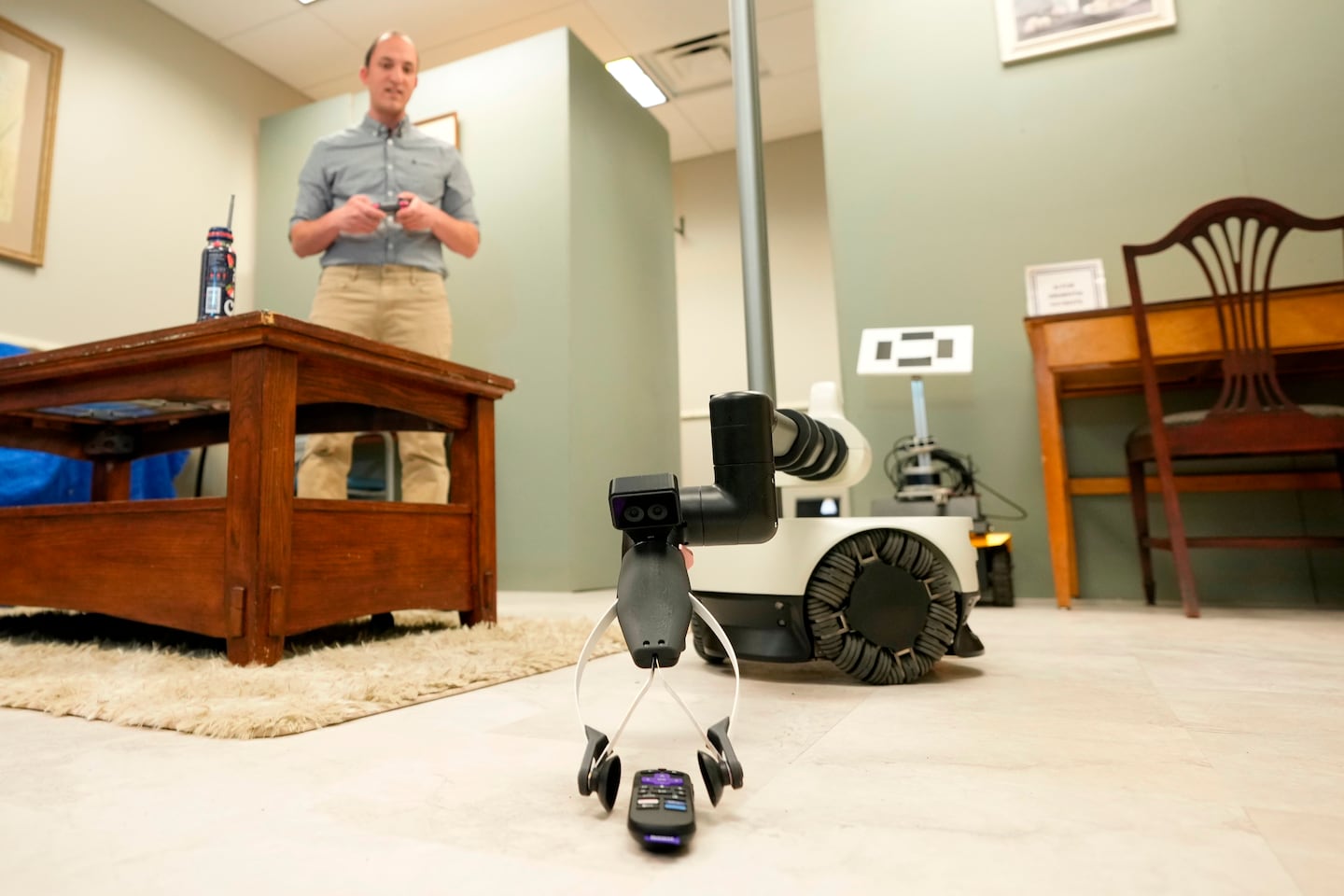 A robot operated by Shehab Attia, a robotics engineer at Hello Robot, reaches to pick up a TV remote during a demonstration at the University of New Hampshire, April 21, in Durham, N.H.