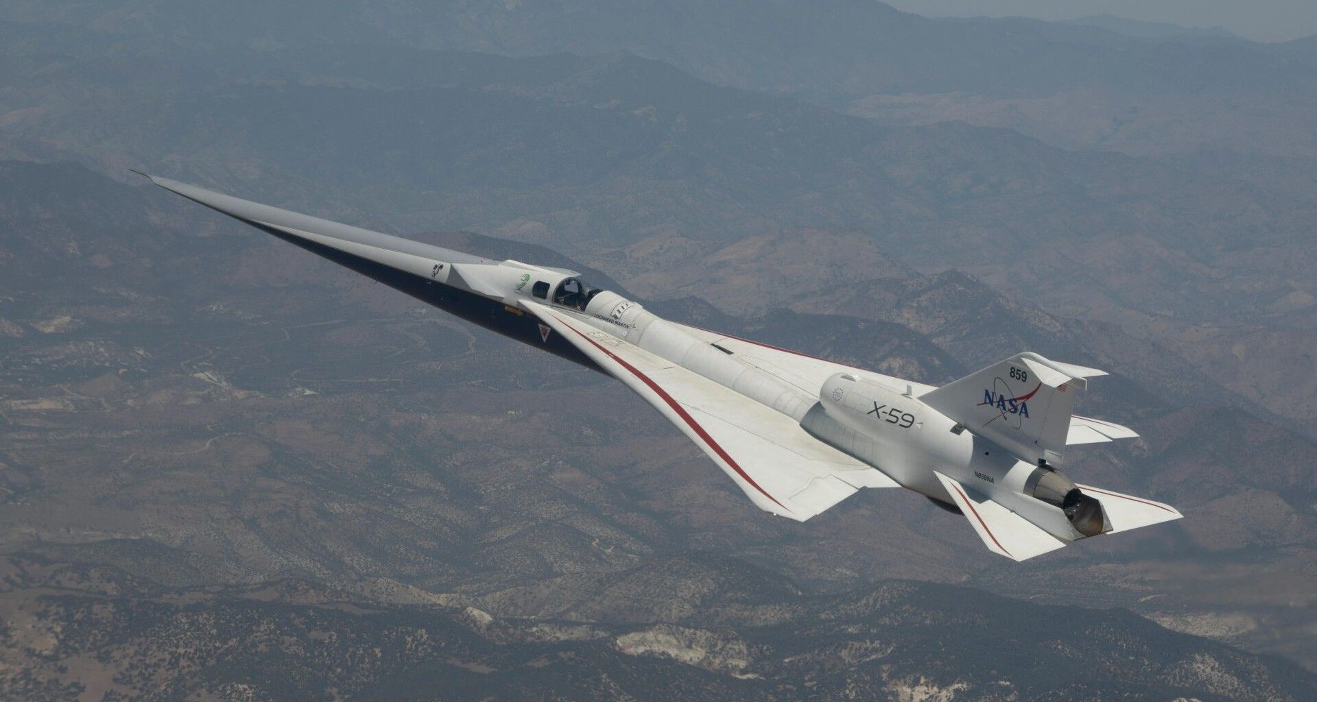 an elongated white jet files above the desert