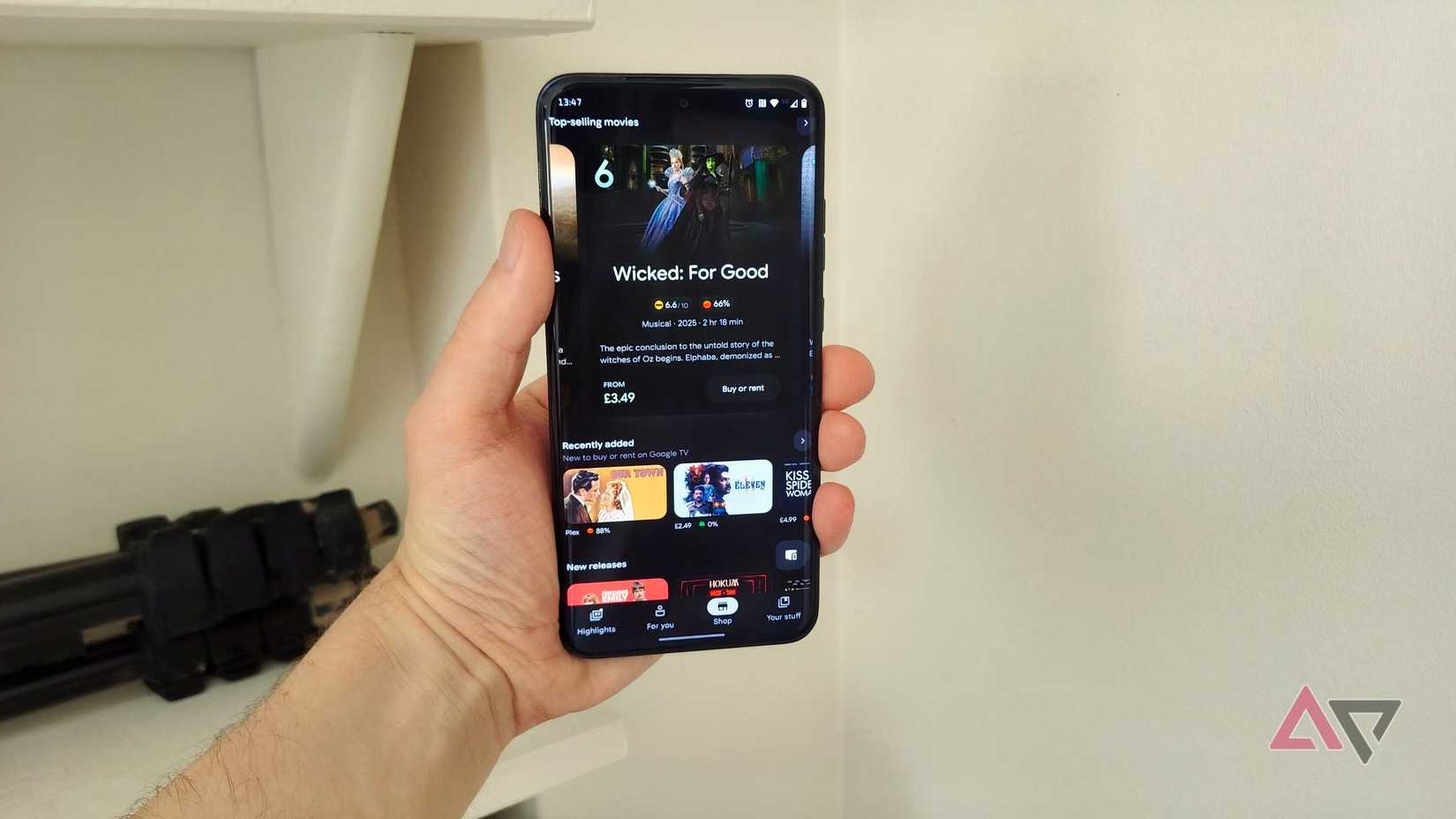 A Motorola phone showing the Google TV menu, with Wicked: For Good listed.