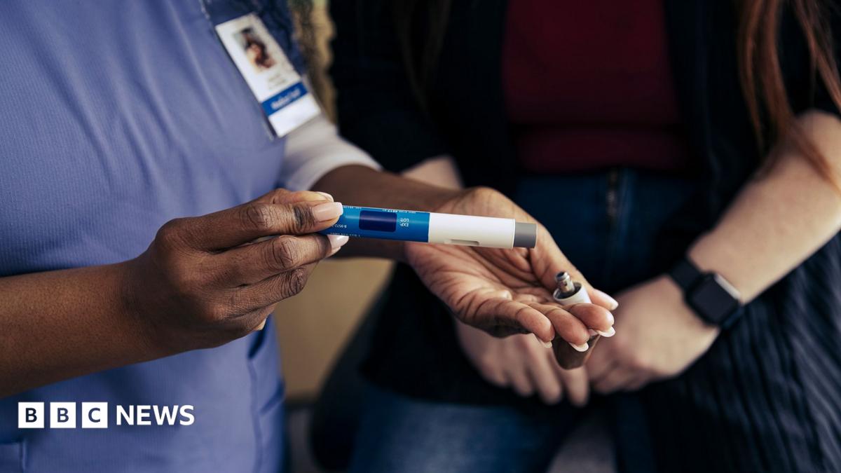 Close-up stock image of a healthcare professional demonstrating to patient how to use a weight loss jab.
