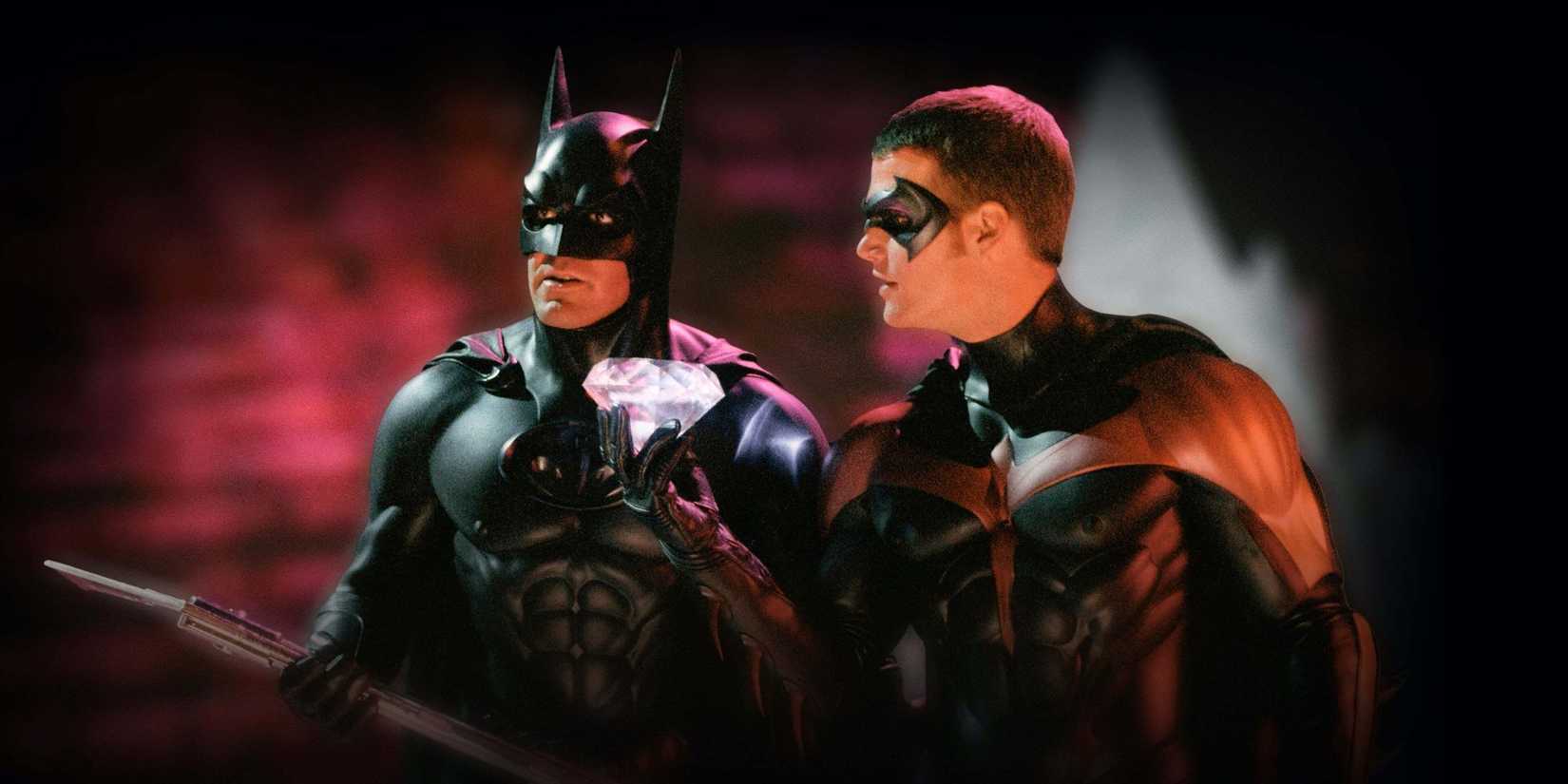 Batman (George Clooney) stands next to Robin (Chris O'Donnell) who holds a large diamond in Batman & Robin
