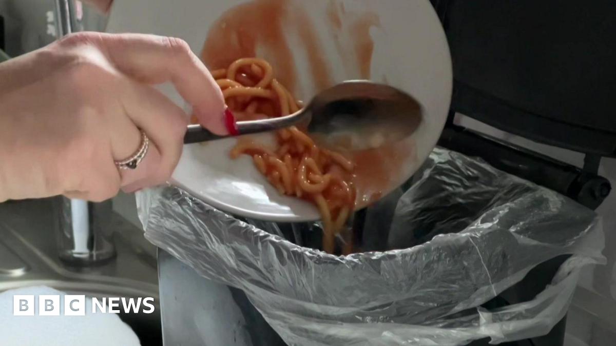 An image of leftover food being scraped into a kitchen food waste caddy