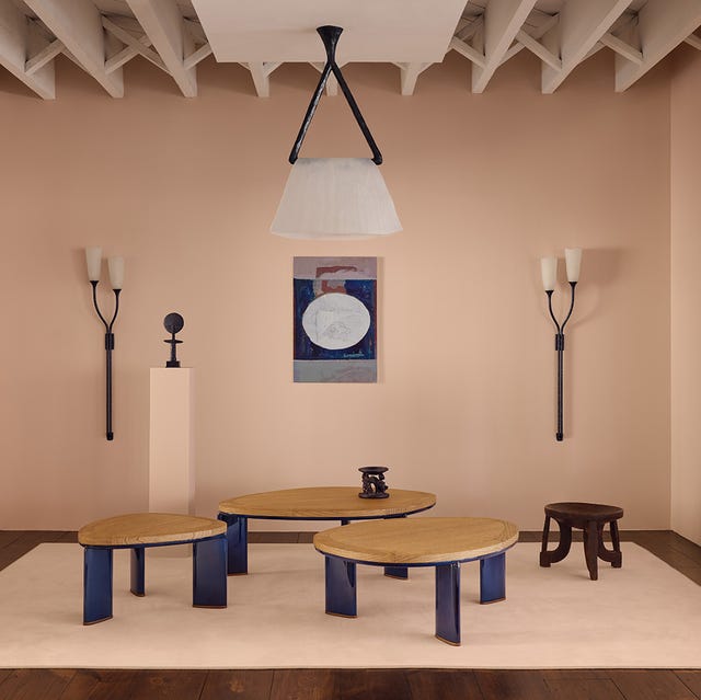 Minimalist room with round wooden tables, wall sconces, pedestal with sculpture, and framed abstract artwork. Minimalist room with round wooden tables, wall sconces, pedestal with sculpture, and framed abstract artwork.