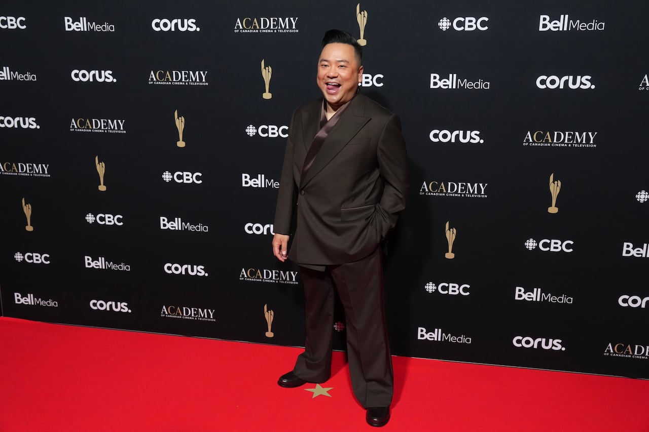 A man poses for a photo wearing a brown suit.