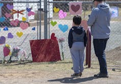 a man and a boy in front of a makeshift memorial
