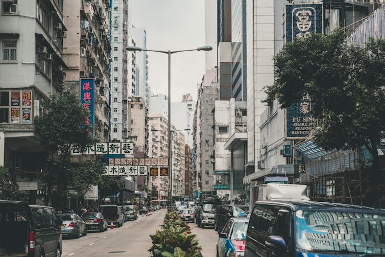 A street scene in Hong Kong featuring cars and trees.