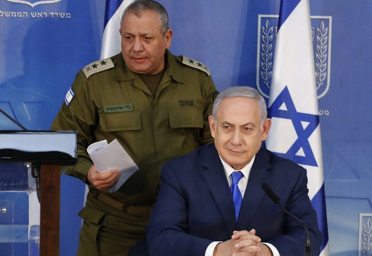 Two men, one in army garb, stand at a lecturn.