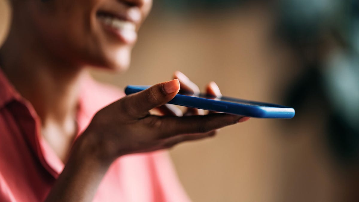 Closeup of a smiling woman speaking into her smartphone