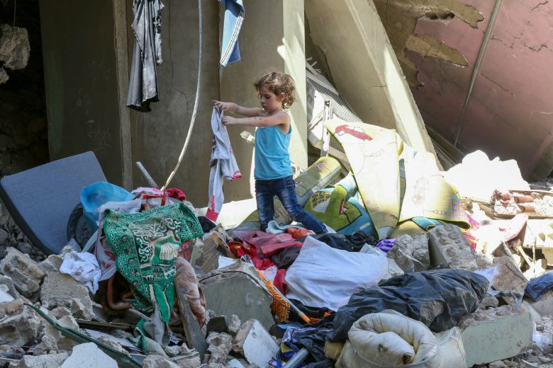 A child searches for salvageable items in the rubble of her home in the southern Lebanese village of Kfar Roummane on June 18, 2026.