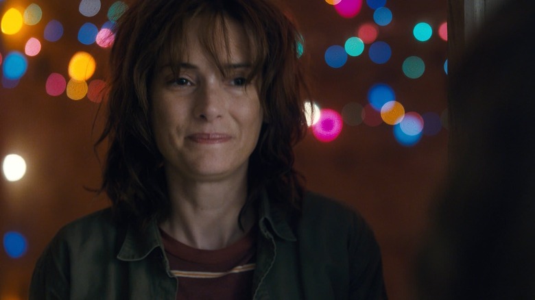 Winona Ryder as Joyce standing in a doorway in front of Christmas lights in Stranger Things